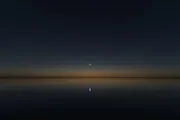 Sirius, the brightest star in the night sky, burning close and clear over a dark still horizon