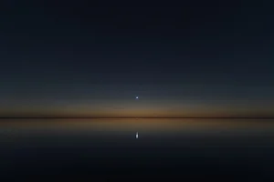 Sirius, the brightest star in the night sky, burning close and clear over a dark still horizon