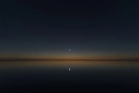 Sirius, the brightest star in the night sky, burning close and clear over a dark still horizon