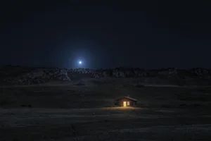 Regulus, the Heart of the Lion, blue-white and low over a dark ridge, a single lit window below it