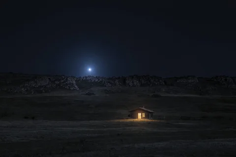 Regulus, the Heart of the Lion, blue-white and low over a dark ridge, a single lit window below it
