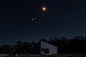 Arcturus, an orange point high above a dark treeline, trailing the handle of the Big Dipper