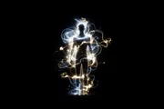 A human silhouette haloed by an exosuit of light in the dark, evoking amplified capability rather than replacement