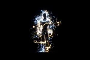 A human silhouette haloed by an exosuit of light in the dark, evoking amplified capability rather than replacement