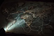 A luminous hand-drawn map of a complex interconnected system with a single flashlight illuminating one corner, evoking making complexity legible rather than simple