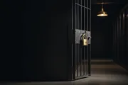 A brass padlock on a dark gate in a server corridor, evoking a password gate at the edge