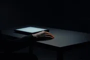A hand resting beside a glowing terminal in the dark, evoking directing an AI agent rather than typing