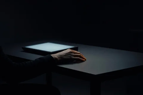 A hand resting beside a glowing terminal in the dark, evoking directing an AI agent rather than typing